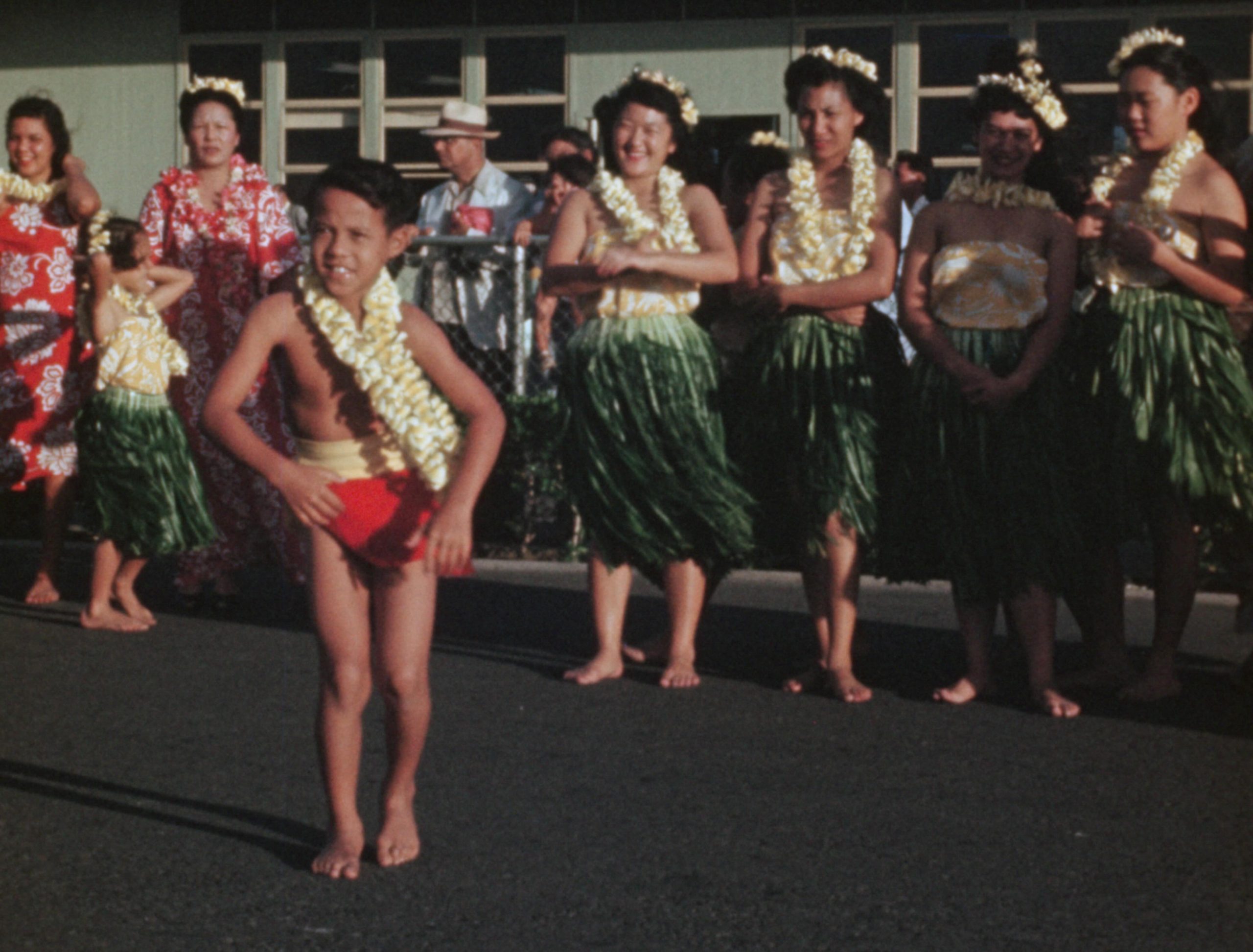 Hula dancers performing, with a young man in the foreground.